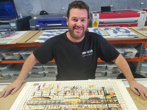 A photo of a man standing over a freshly cut puzzle